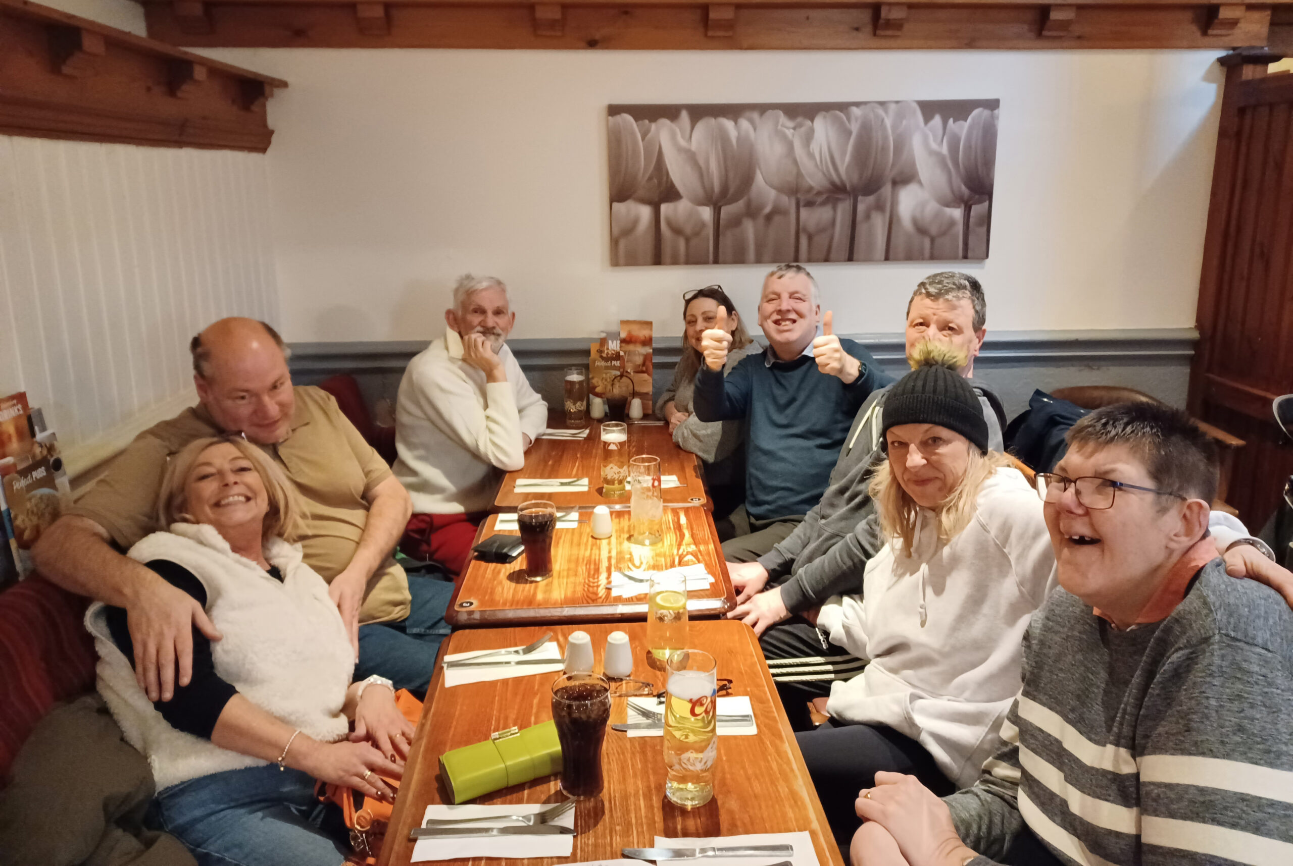 A photograph of 9 people sitting around a table at the pub